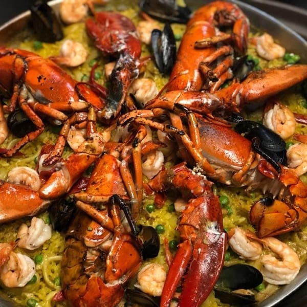 Close-up of a Spanish paella with large lobsters, shrimp, mussels, and green peas.