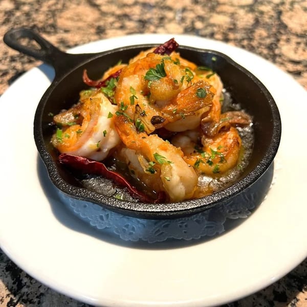 Guardado's Spanish garlic shrimp (Gambas al Ajillo) in a small cast iron skillet on a white plate.